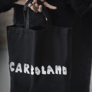 Czarna, bawełniana torba z białym napisem Carboland na środku. W prawym dolnym rogu torby logo Muzeum Emigracji.