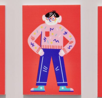Czerwony magnes. Magnes z ilustracją wisi na okapie w kuchni. Na ilustracji na czerwonym tle Franek – bohater wystawy. Ubrany w różowy sweter i niebieskie spodnie. Stoi z założonymi na biodra rękami.